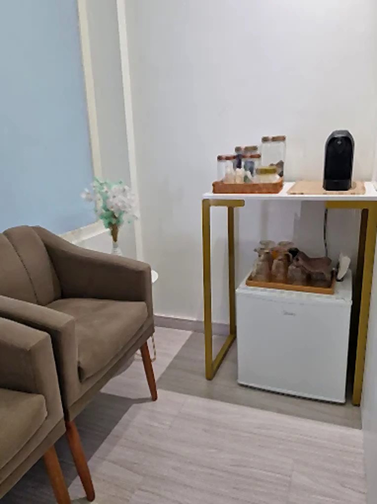 Recepção do consultório, com poltronas, café e água